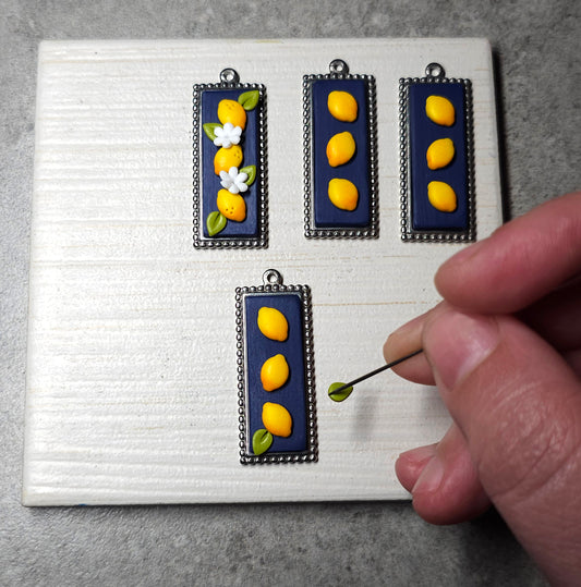 Μακρύ ατσάλινο κολιέ με κίτρινα λεμόνια σε μπλε φόντο από πολυμερικό πηλό