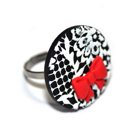 Στρογγυλό δαχτυλίδι λευκή δαντέλα σε μαύρο φόντο με κόκκινο φιογκάκι